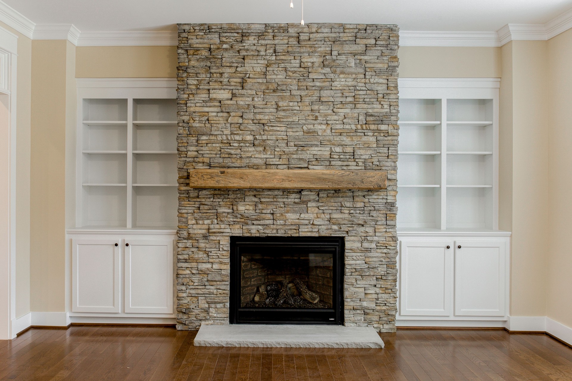 Spacious Living Room with Stone Fireplace and Large Windows Providing Light, Built in Shelves